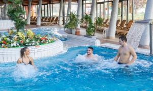 un hombre y una mujer sentados en una piscina en Deluxe Thermal Resort, en Pápa