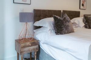 a bed with white sheets and a lamp on a night stand at York Riverside Apartments in York