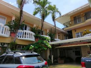a car parked in front of a building with palm trees at Hotel Malinche in Quepos