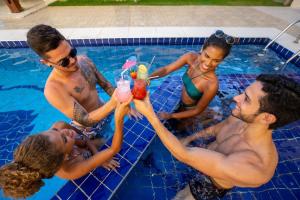 a group of people in a swimming pool drinking cocktails at Pousada Paris in Praia do Frances