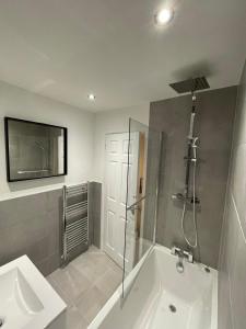 a bathroom with a shower and a tub and a sink at Cannock, Modern 2 bed house, Perfect for contractors, Business Travellers, Short Stays, Driveway for 2 vehicles, Close to M6, M54/i54, A5.A38. McArthur Glen Designer Outlet in Cannock