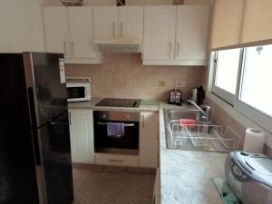 una cucina con armadietti bianchi e frigorifero nero di No3,23 Neilmmantos St Peyia a Peyia