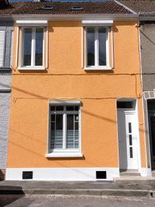 ein orangefarbenes Gebäude mit zwei Fenstern und einer weißen Tür in der Unterkunft Gîte Cœur d'Opale, seul hébergement 4 étoiles sur Étaples in Étaples