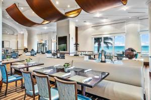 um restaurante com mesas e cadeiras e o oceano em Palm Beach Singer Island Resort & Spa Luxury Suites em Riviera Beach