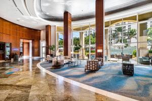 eine Lobby mit Stühlen und Tischen in einem Gebäude in der Unterkunft Palm Beach Singer Island Resort & Spa Luxury Suites in Riviera Beach