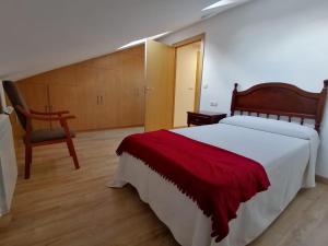 1 dormitorio con 1 cama con manta roja y silla en Casa en el centro histórico de Corcubión., en Corcubión