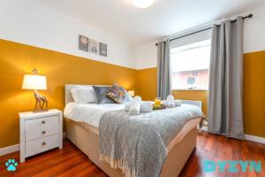 a bedroom with yellow walls and a bed and a window at Henke Court - DYZYN Living - Pet Friendly , Balcony & Secured Parking - B2B Long Stay in Cardiff