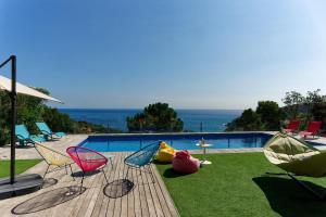 ベグールにあるVilla Sa Riera Begur vue mer panoramique et plage à piedsのスイミングプールの横に座る椅子