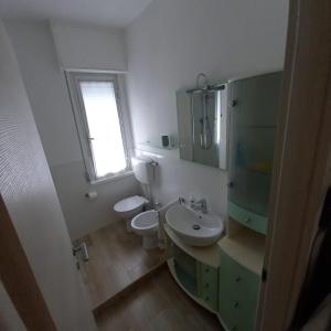 ein Bad mit einem Waschbecken, einem WC und einem Fenster in der Unterkunft casa vacanza fronte mare fano sassonia in Fano