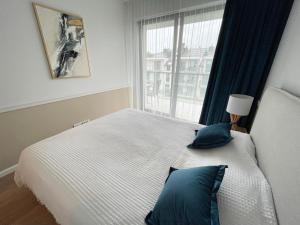 une chambre avec un lit avec des oreillers bleus et une fenêtre dans l'établissement Nadmorska ucieczka Niechorze - Niechorze Seaside Getaway - Rezydencja Niechorze, à Niechorze
