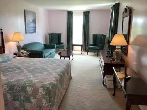 a hotel room with a bed and chairs and a television at Rollo Bay Inn in Souris