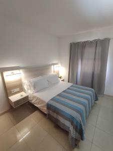 Un dormitorio con una cama grande con una manta a rayas. en FLOR DE PASCUA, en Acantilado de los Gigantes