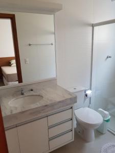ein Badezimmer mit einem Waschbecken, einem WC und einem Spiegel in der Unterkunft Apartamento Beira-Mar, Paraíso dos Pataxós. in Porto Seguro