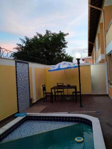 eine Terrasse mit einem Tisch und einem Sonnenschirm neben einem Pool in der Unterkunft Apartamento Beira-Mar, Paraíso dos Pataxós. in Porto Seguro