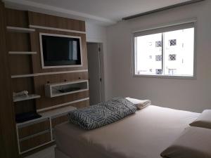 a bedroom with a bed and a tv and a window at Apto alto padrão in Balneário Camboriú