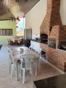 a kitchen with a table and a brick fireplace at Casa Morada da Praia in Boracéia