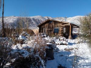 a log cabin with snow in front of it at Posta Nehuen Tomillo in Potrerillos