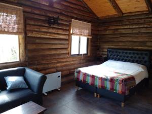 a bedroom with a bed and a chair in a log cabin at Posta Nehuen Tomillo in Potrerillos