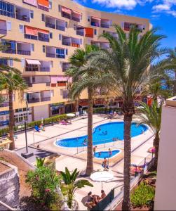 an apartment with a swimming pool in front of a building at Los Cristianos El Carmen in Los Cristianos