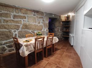 a dining room with a table and chairs and a stone wall at Zimão Garden House in Vila Real +19 photos