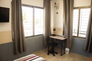 a bedroom with a desk and two windows and a bed at Departamento Orellana 11 in Chetumal