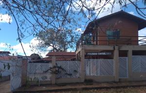 un edificio detrás de una valla blanca con un cartel. en Pousada Central en Santana do Riacho