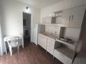 een keuken met witte kasten, een bureau en een tafel bij Marco Zero Containers 2 in Balneário Camboriú