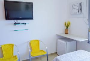 Habitación con 2 sillas amarillas y TV. en Apart Hotel em Carneiros, Tamandaré., en Tamandaré