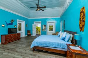 a blue bedroom with a bed and a ceiling fan at Victoria House in Frederiksted