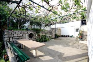 un banco sentado bajo una pérgola junto a una pared de piedra en Guesthouse Drašković, en Petrovac na Moru