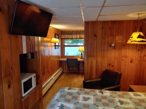 Lakeshore Motel Ice Lake في Iron River: غرفة بسرير وتلفزيون وطاولة