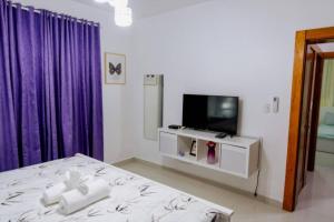 - une chambre avec un lit, une télévision et des rideaux violets dans l'établissement Hermoso apartamento, 3 Habitaciones espaciosas, 2 Aires acondicionados, à Santiago de los Caballeros