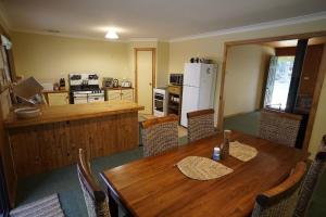 cocina y comedor con mesa de madera y sillas en Karriwood Cottage, en Pemberton
