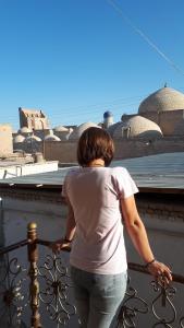 Una mujer parada en una valla mirando el océano en Guest House Art Postindoz, en Khiva