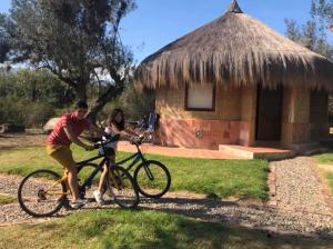 Ein Mann und eine Frau auf einem Fahrrad vor einer Hütte in der Unterkunft Chalets Sol Muisca RNT85322 in Villa de Leyva