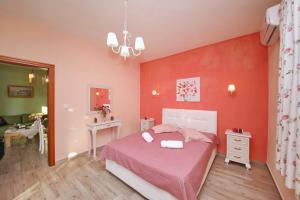 1 dormitorio con paredes rojas y 1 cama con sábanas rosas en Koromilia Villa, en Neo Klima