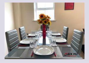 a dining room table with a vase of sunflowers on it at Chichele House, sleeps 8, allocated parking, pets, free wi-fi, corporate welcome in Higham Ferrers