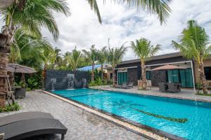 a swimming pool in front of a house with palm trees at Coco Pina in Prachuap Khiri Khan