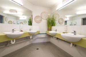 La salle de bains est pourvue de 3 lavabos et de 2 miroirs. dans l'établissement Sow and Piglets Guesthouse, à Port Campbell