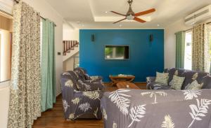 a living room with two couches and a blue wall at The Garden Villas - La Digue in La Digue