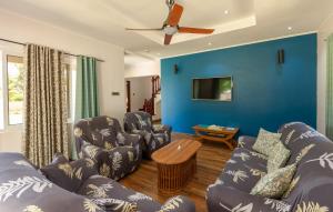 una sala de estar con paredes azules y sofás en The Garden Villas - La Digue, en La Digue