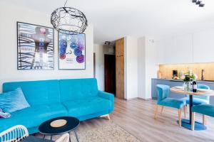 a living room with a blue couch and a table at Apartamenty Kozubnik - Apartament 16 z dużym tarasem in Porąbka