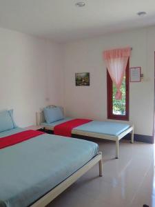 1 dormitorio con 2 camas y ventana en Thanathorn Guesthouse en Trang