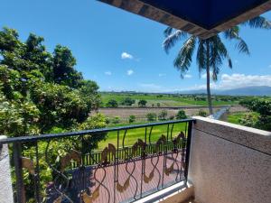 a balcony with a view of a field and a palm tree at Starry Night in Taitung City +13 photos