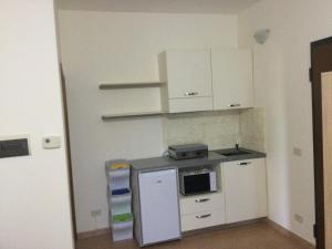 a small kitchen with white cabinets and a microwave at Appartamento Turistico FRAU in Sinalunga