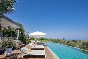 een zwembad met ligstoelen en een parasol bij Villa Amnalys in Amnátos