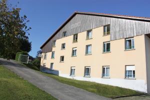 a large tan building with a black roof at Azureva Métabief in Métabief