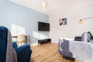 a living room with two chairs and a tv at City of the Kings - Indigo Apartment in Kraków
