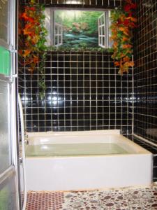 a black tiled bathroom with a bath tub and a window at Mimatsuso Ryokan in Asahikawa