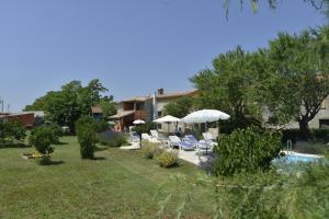 um quintal com cadeiras e guarda-sóis e uma piscina em Villa Vodnjan (3556) em Vodnjan